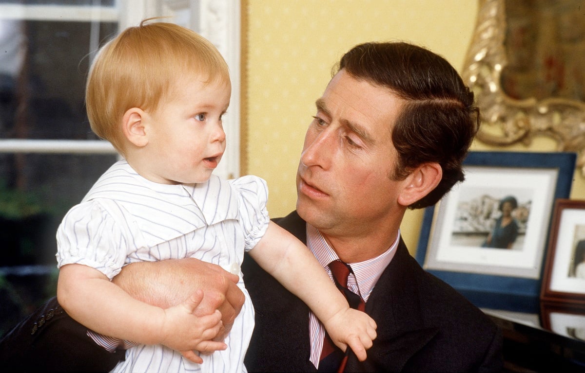 Then-Prince Charles holding a young Prince Harry at Kensington Palace