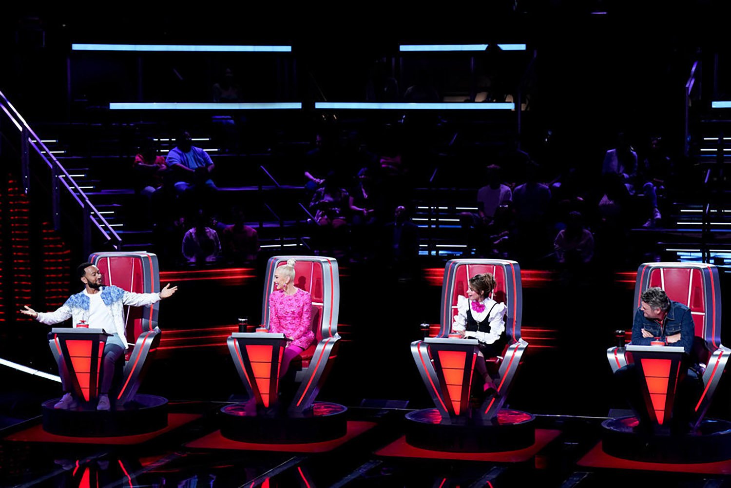 Coaches John Legend, Gwen Stefani, Camila Cabello, and Blake Shelton sitting in chairs on 'The Voice' Season 22