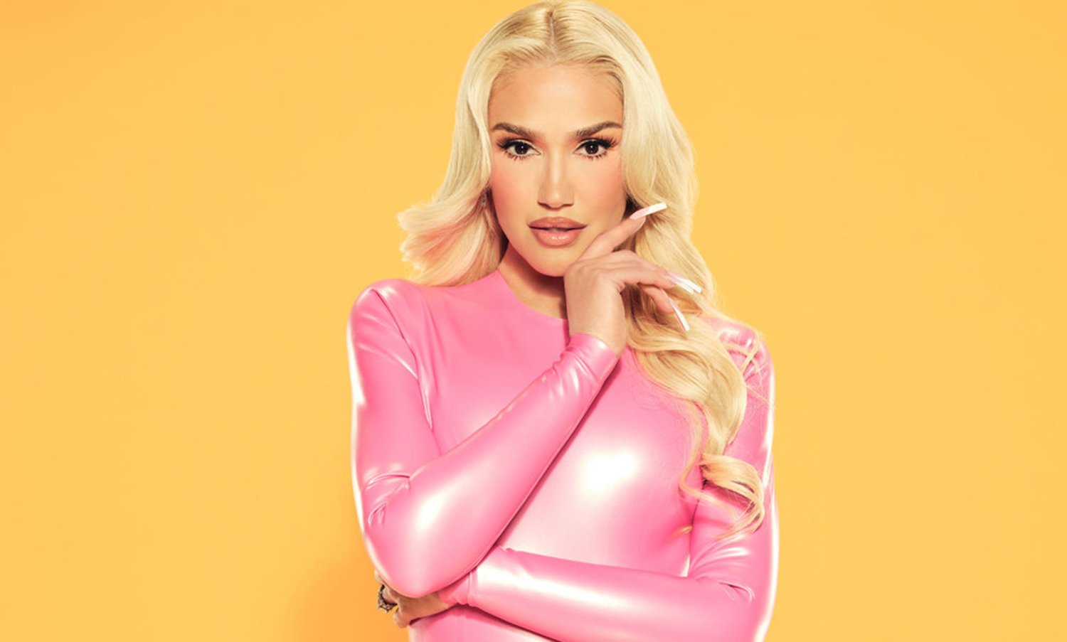 Gwen Stefani poses in a pink dress against a yellow backdrop for The Voice Season 22