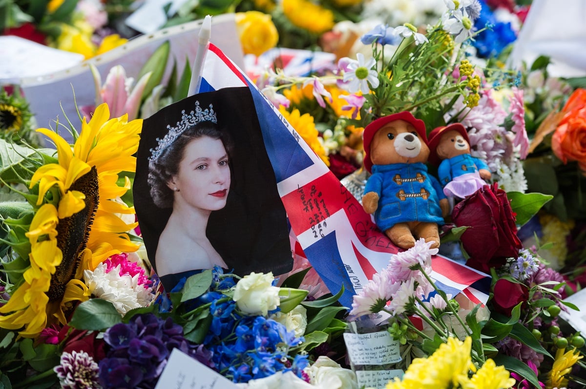 A portrait of Queen Elizabeth II is placed next to Union Jack flag and Paddington teddy bears tributes in London following her death