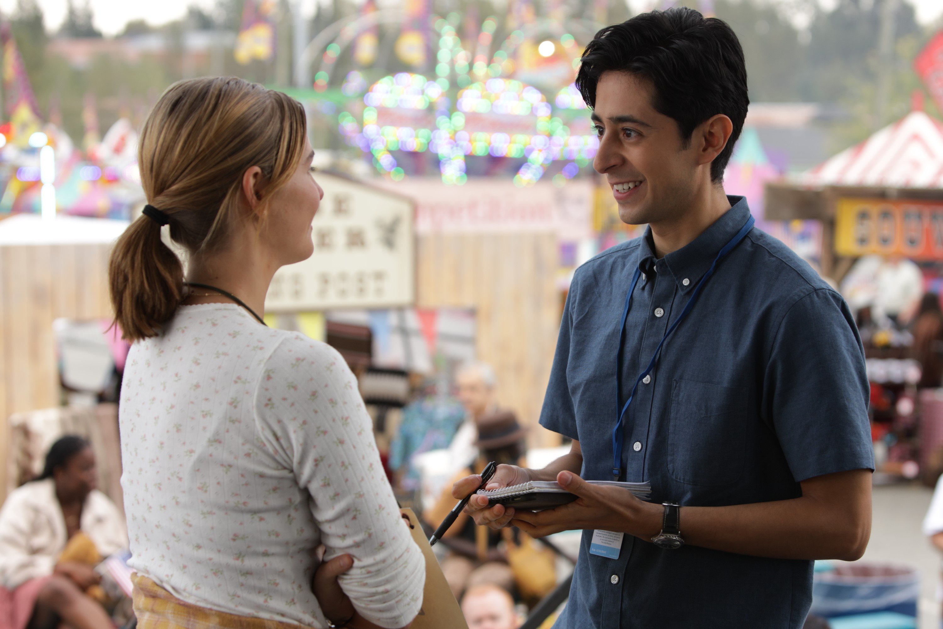 Stephanie Scott and Pablo Castelblanco, in character as Erica and Gabriel in 'Alaska Daily' Season 1 Episode 4, share a scene. Erica wears a white long-sleeved shirt. Gabriel wears a dark blue short-sleeved button-up shirt.