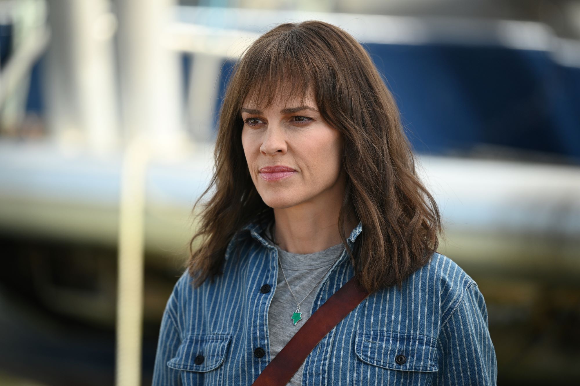 Hilary Swank, in character as Eileen in the show 'Alaska Daily' on ABC, wears a blue and white striped button-up shirt over a light gray shirt.