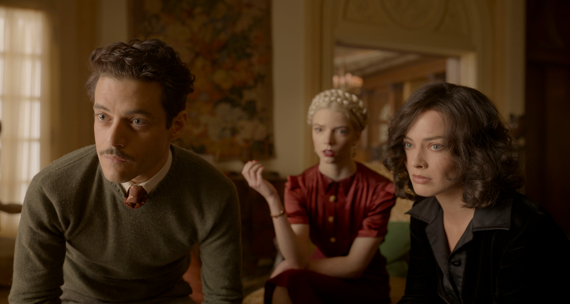 'Amsterdam' Rami Malek as Tom Voze, Anya Taylor-Joy as Libby Voze, and Margot Robbie as Valerie Voze all looking slightly concerned wearing 1930s clothing in gaudy living room