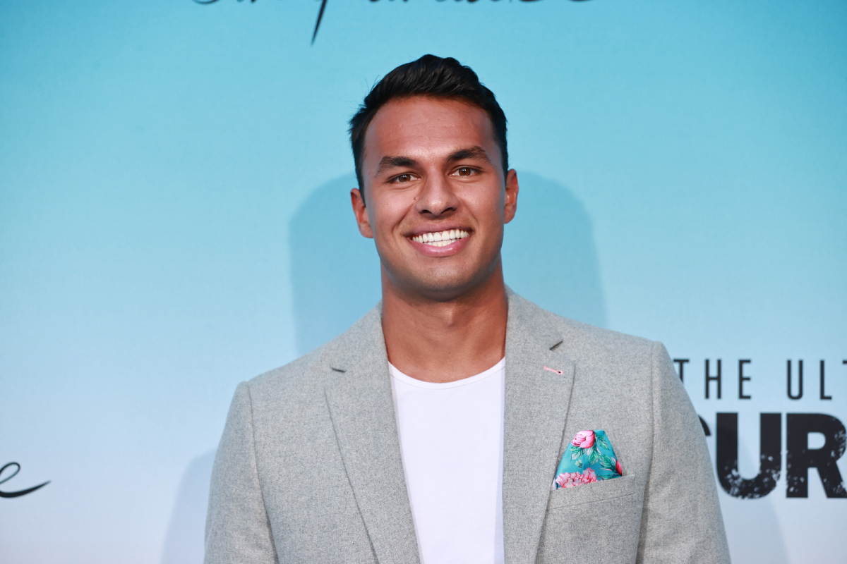 Aaron Clancy returns for Bachelor in Paradise Season 8. Aaron wears a white shirt and grey suit jacket.