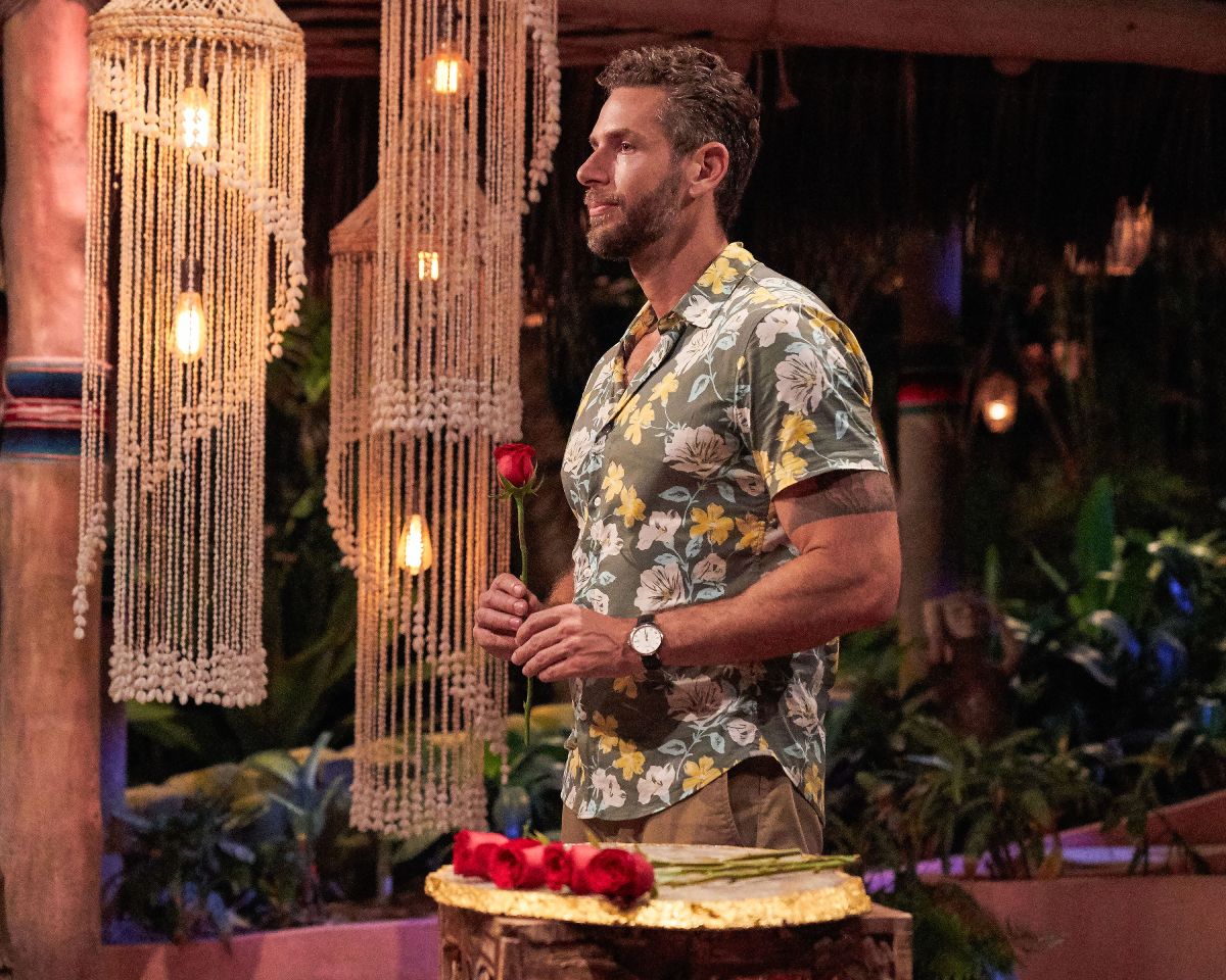 Casey Woods during the rose ceremony on Bachelor in Paradise Season 8. Casey wears a floral button-down shirt and holds a rose.