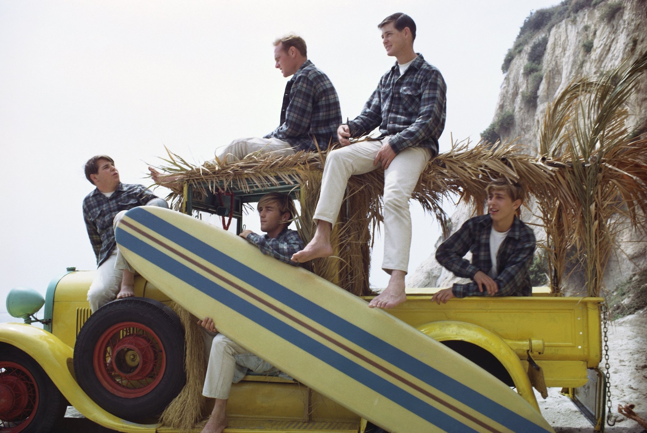 Rock and roll band The Beach Boys pose for a portrait with a vintage 'Woody' station wagon