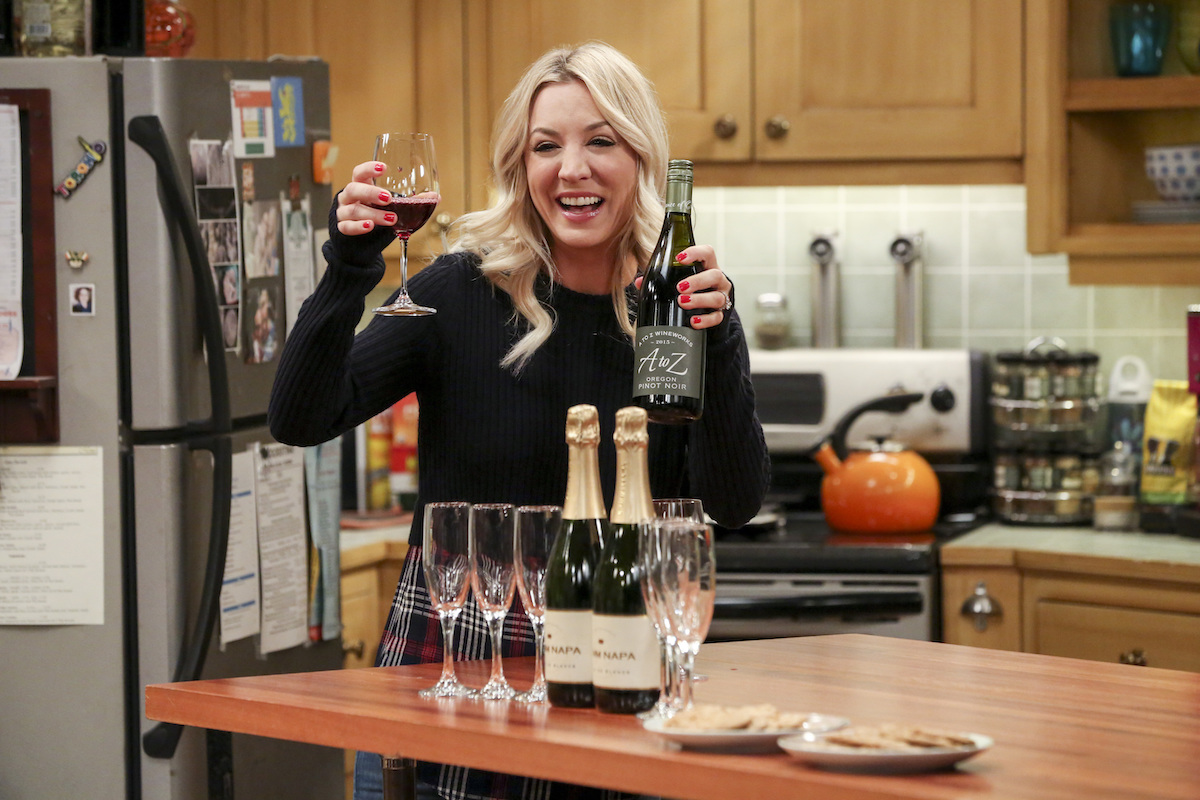 「ビッグバン セオリー」: ペニー (ケイリー クオコ) がワインのボトルとグラスを持ち上げる