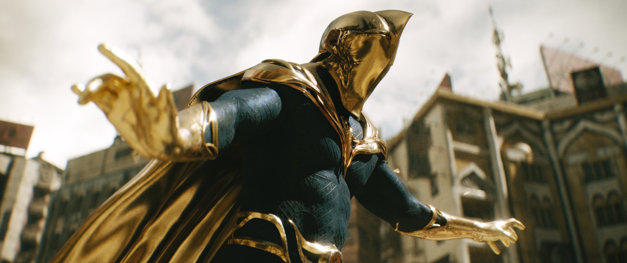 'Black Adam' Pierce Brosnan as Dr. Fate wearing a gold and black costume, holding his hand out and wearing a golden helmet.
