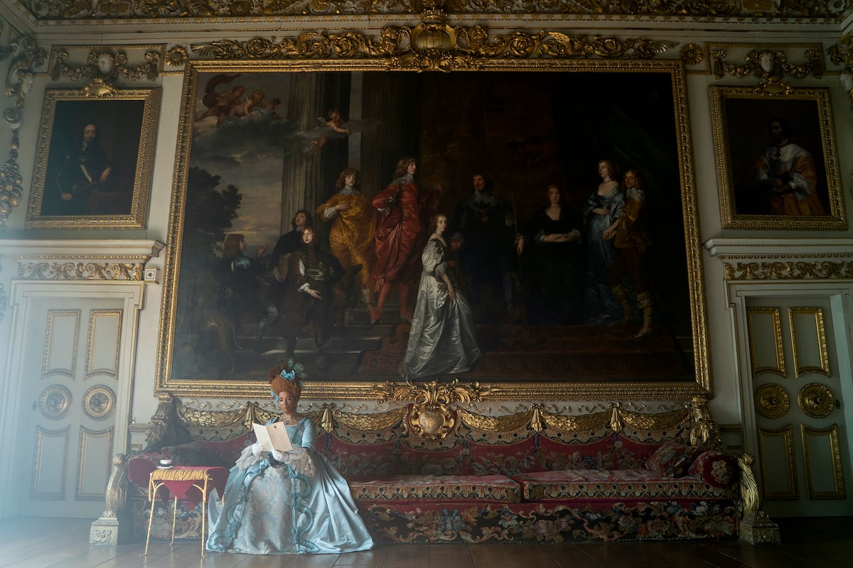 'Bridgerton' actor Golda Rosheuvel as Queen Charlotte reading in a gilded room