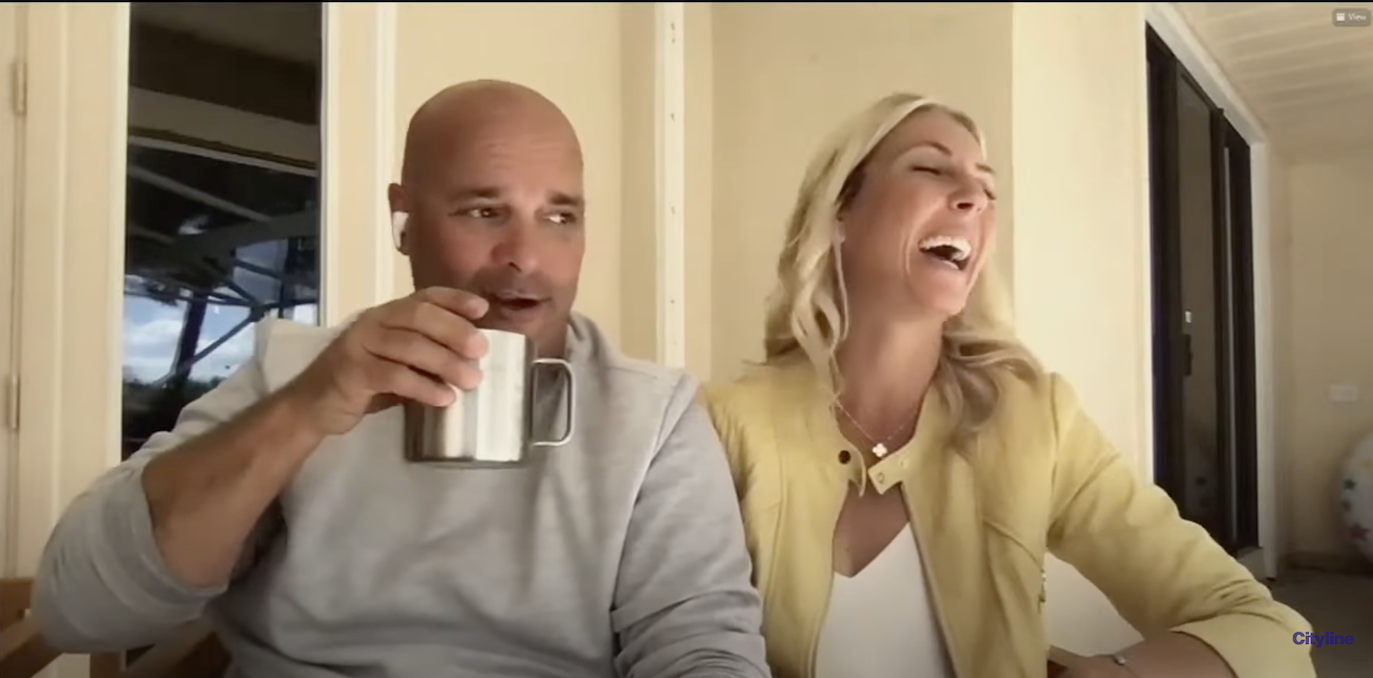Bryan Baeumler and Sarah Baeumler from 'Renovation Island' sitting next to each other and laughing during an interview