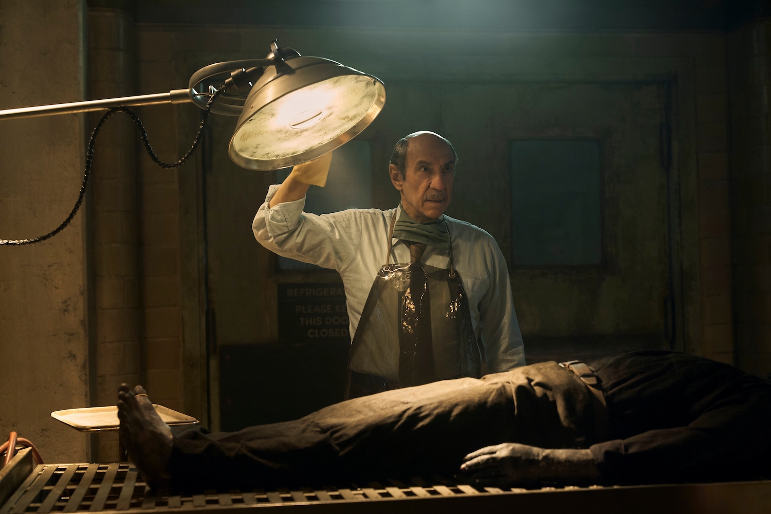 'Cabinet of Curiosities' episode 'The Autopsy' stars F. Murray Abraham seen here shining a light over a corpse wearing a coroner's apron.