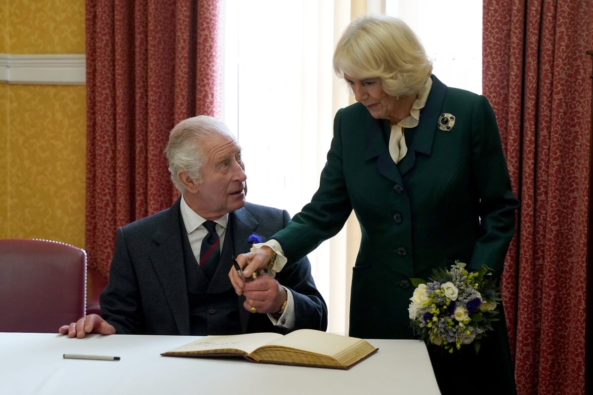 King Charles III and Camilla Parker Bowles, Queen Consort, sign a visitor's book as they attend an official council meeting at the City Chambers in Dunfermline, Fife, to formally mark the conferral of city status on the former town on October 3, 2022 in Dunfermline, Scotland