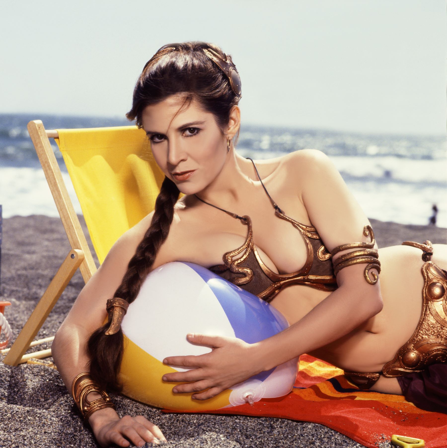 Carrie Fisher as Princess Leia from Star Wars in a gold bikini with an inflatable beach ball