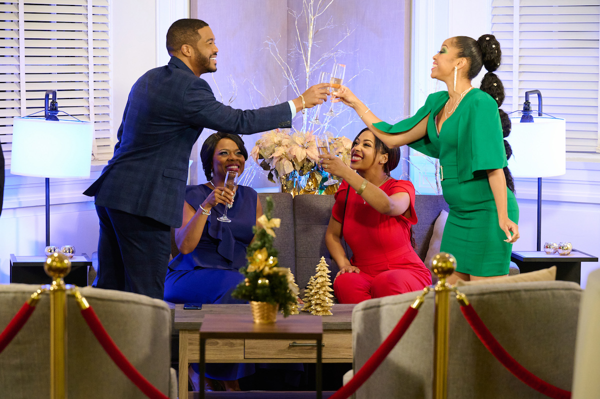 Two people toasting while two women look in the BET+ Christmas movie 'Christmas Party Crashers
