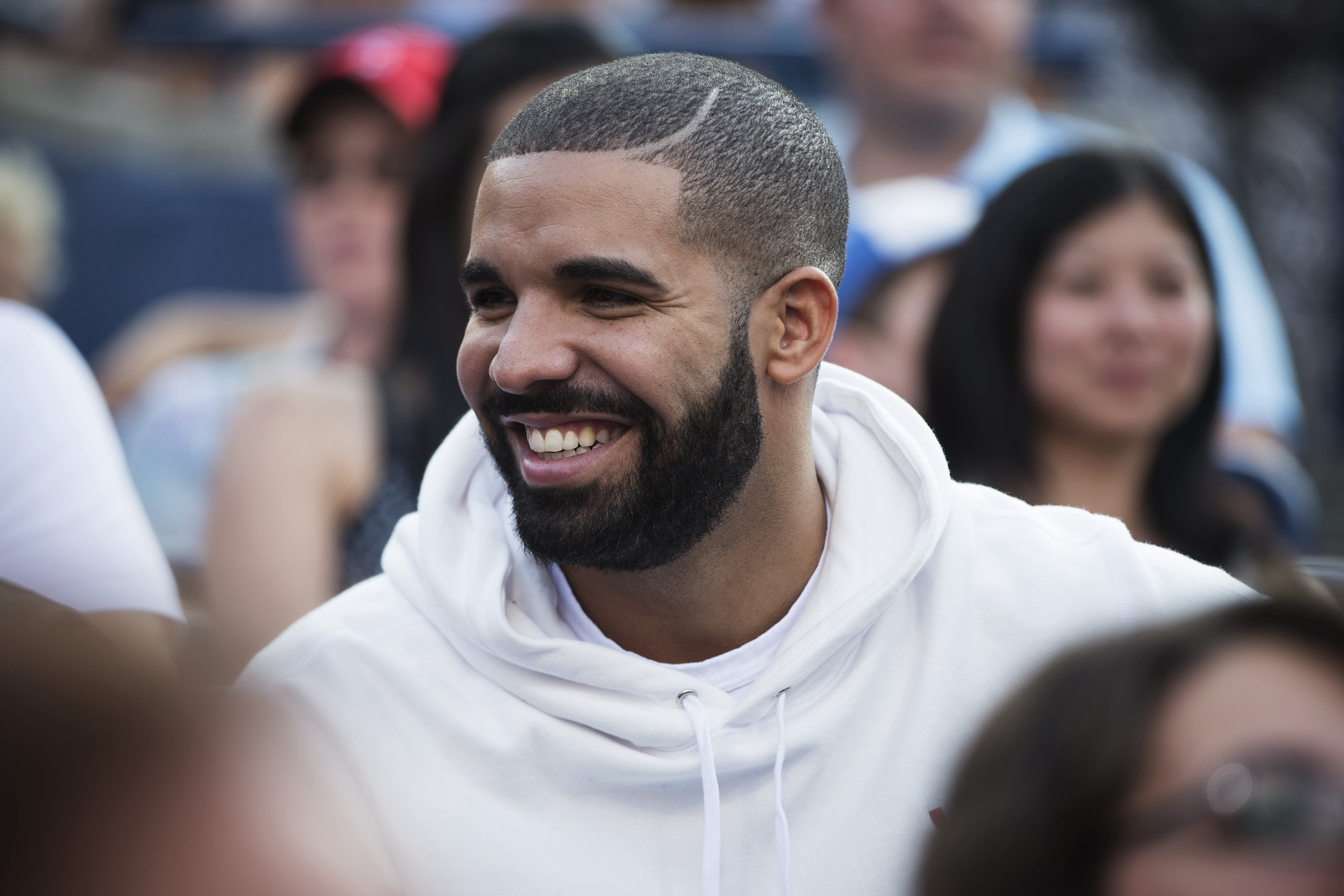 Drake, who was once linked to Serena Williams, smiling and wearing a white hoodie