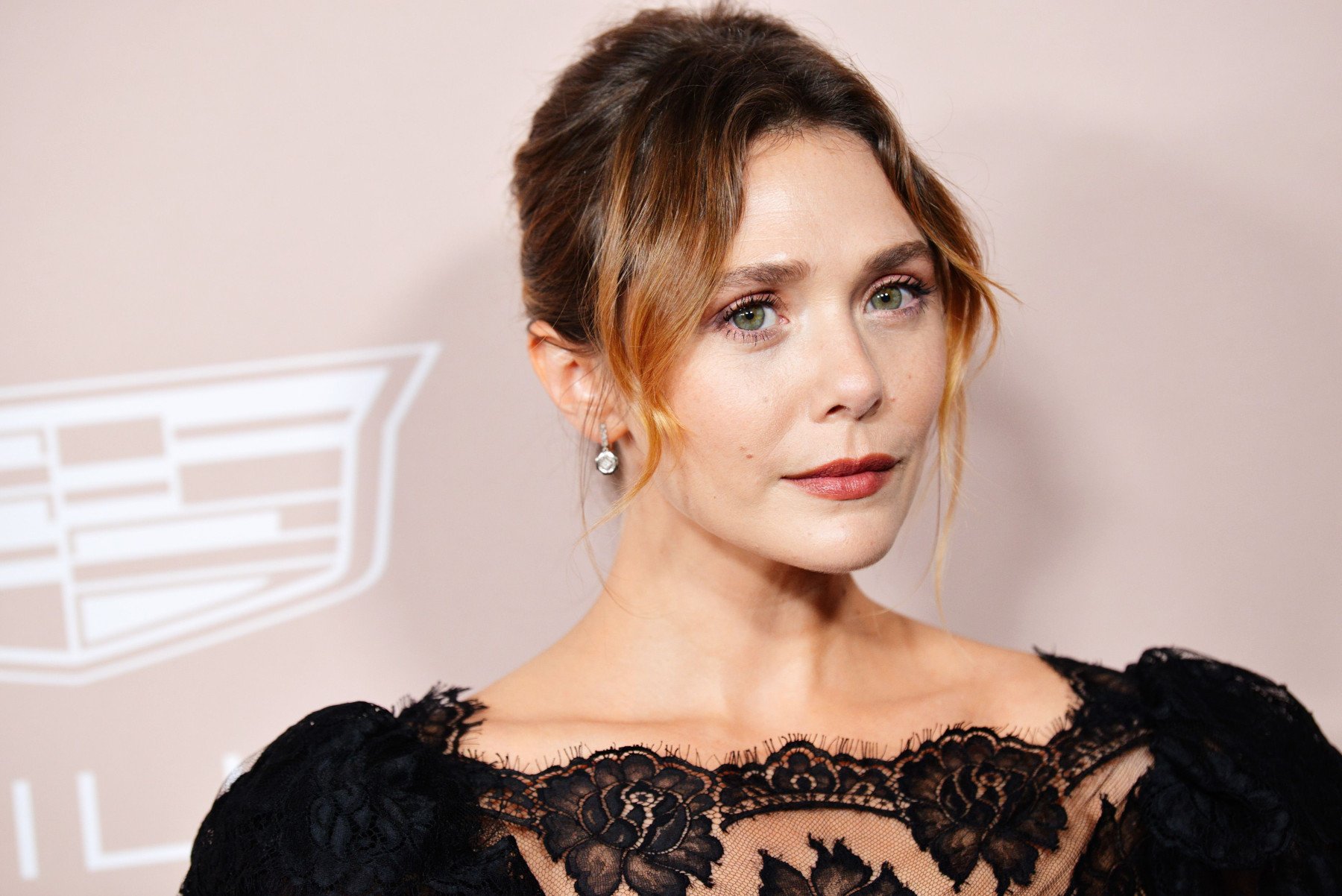 Elizabeth Olsen, who recently addressed rumors that she was cast in 'House of the Dragon.' She's wearing a black dress with lace on the top, and her hair is pulled back.