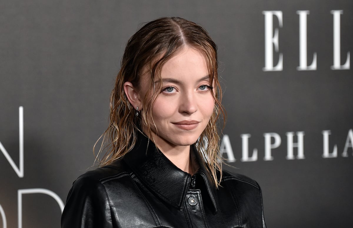 'Euphoria' actor Sydney Sweeney smiling and wearing a black jacket while posing at an event.

