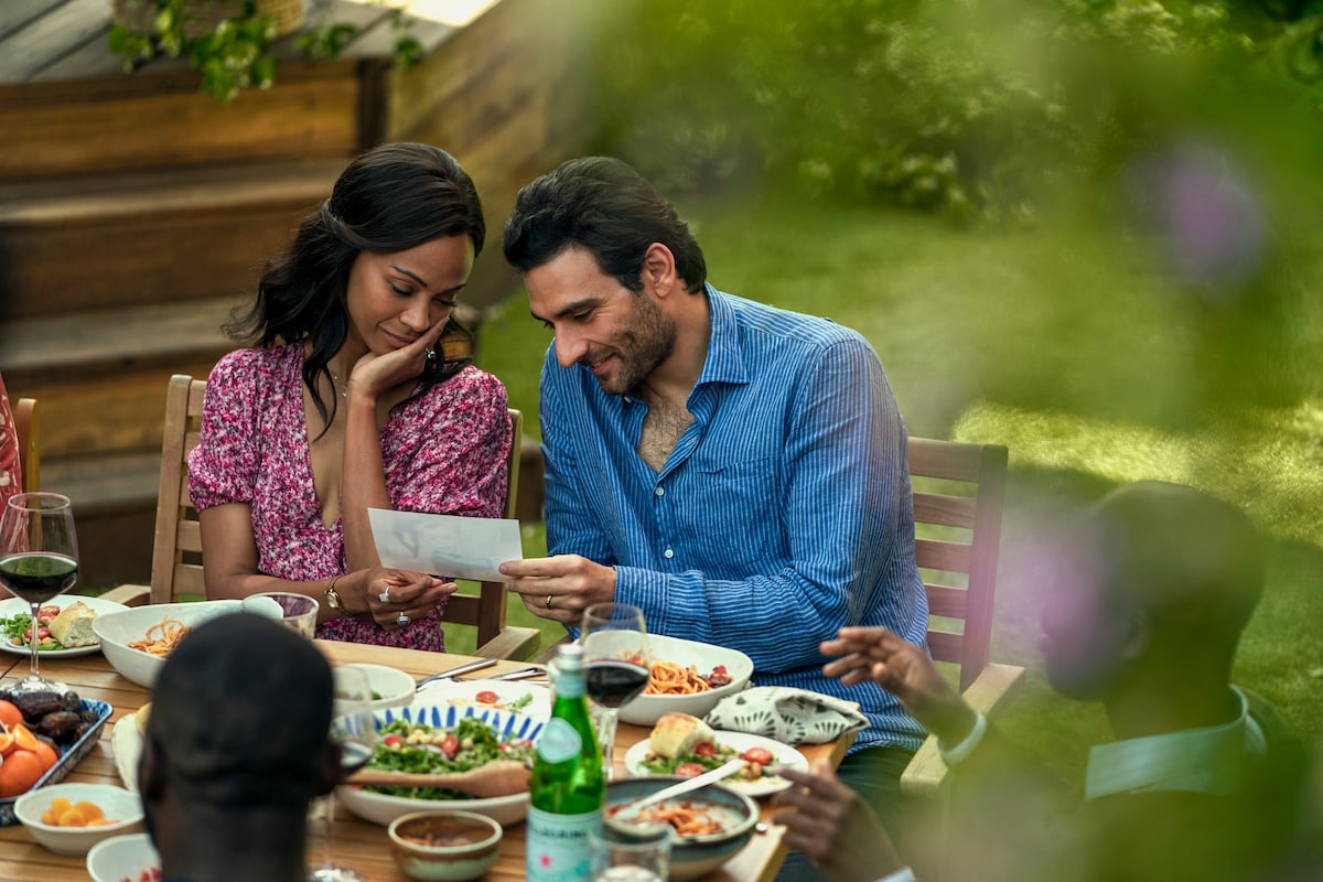 Zoe Saldana as Amy Wheeler and Eugenio Mastrandrea as Lino Ortolano looking at a photograph over a picnic tablein 'From Scratch'