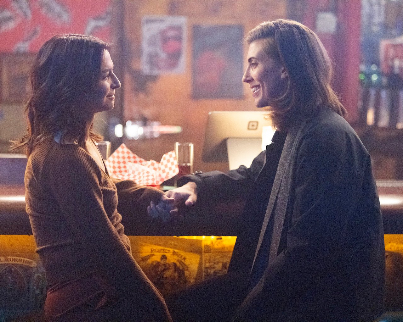 Caterina Scorsone as Amelia and E.R. Fightmaster as Kai sit at a bar together on 'Grey's Anatomy'.