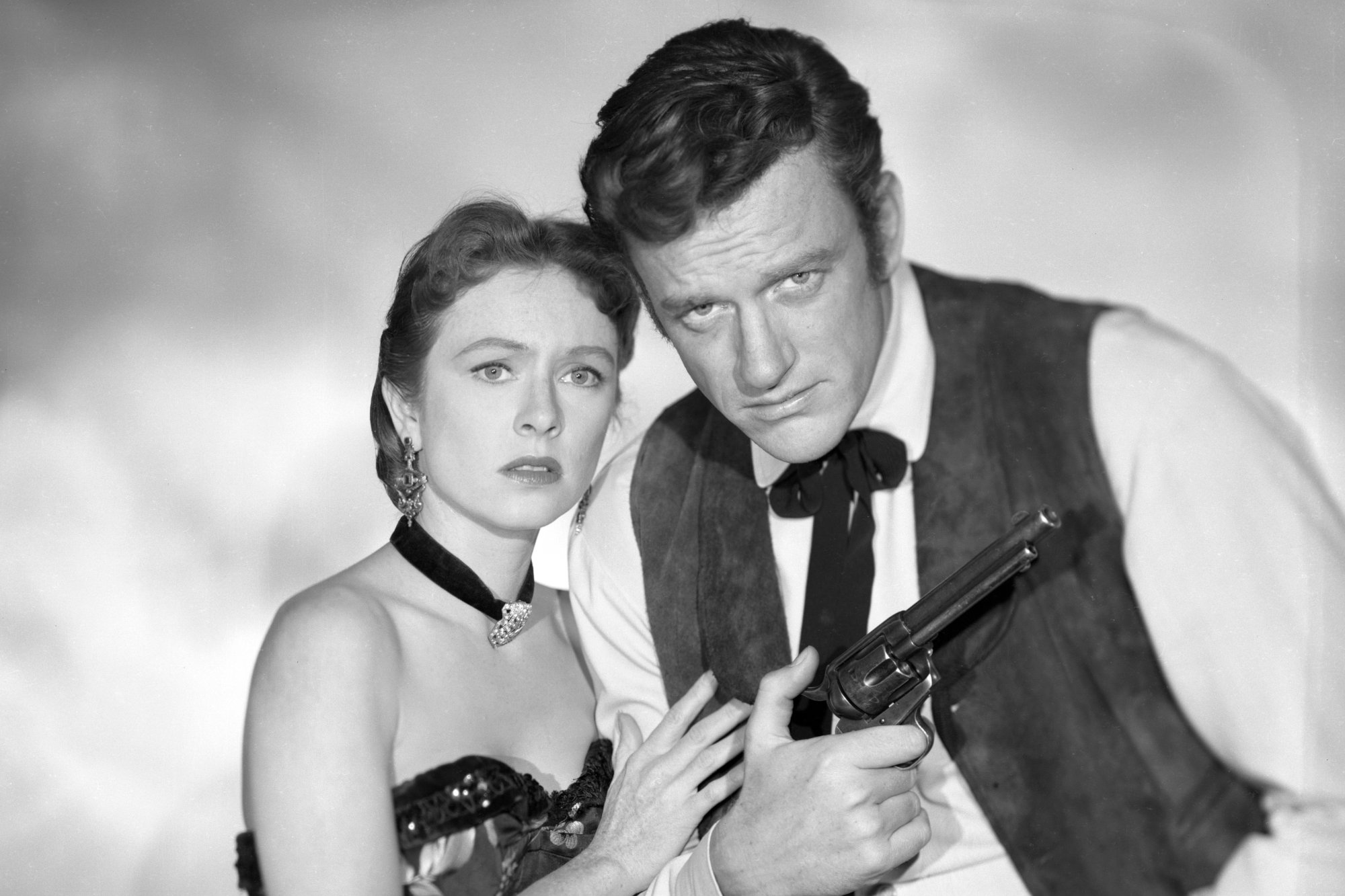 'Gunsmoke' Amanda Blake as Kitty Russell and James Arness as Marshal Matt Dillon. Blake is holding onto Arness' arm looking concerned. He's holding a pistol.
