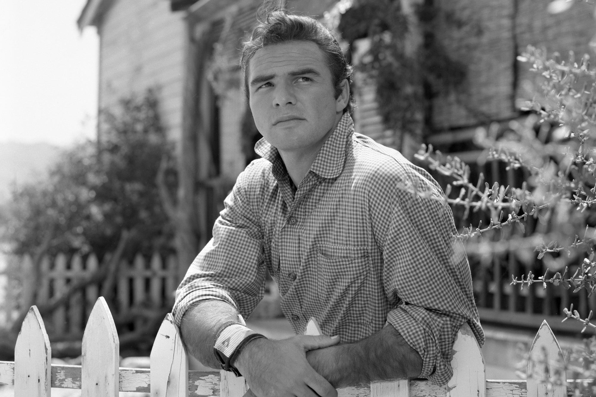 'Gunsmoke' Burt Reynolds as Quint Asper leaning on a white picket fence in a black-and-white photograph