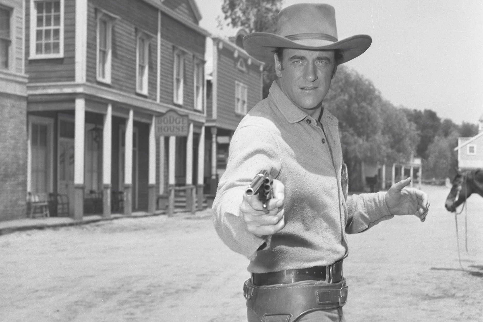 'Gunsmoke' James Arness as Marshall Matt Dillon wearing his Western costume and holding out his gun toward the camera