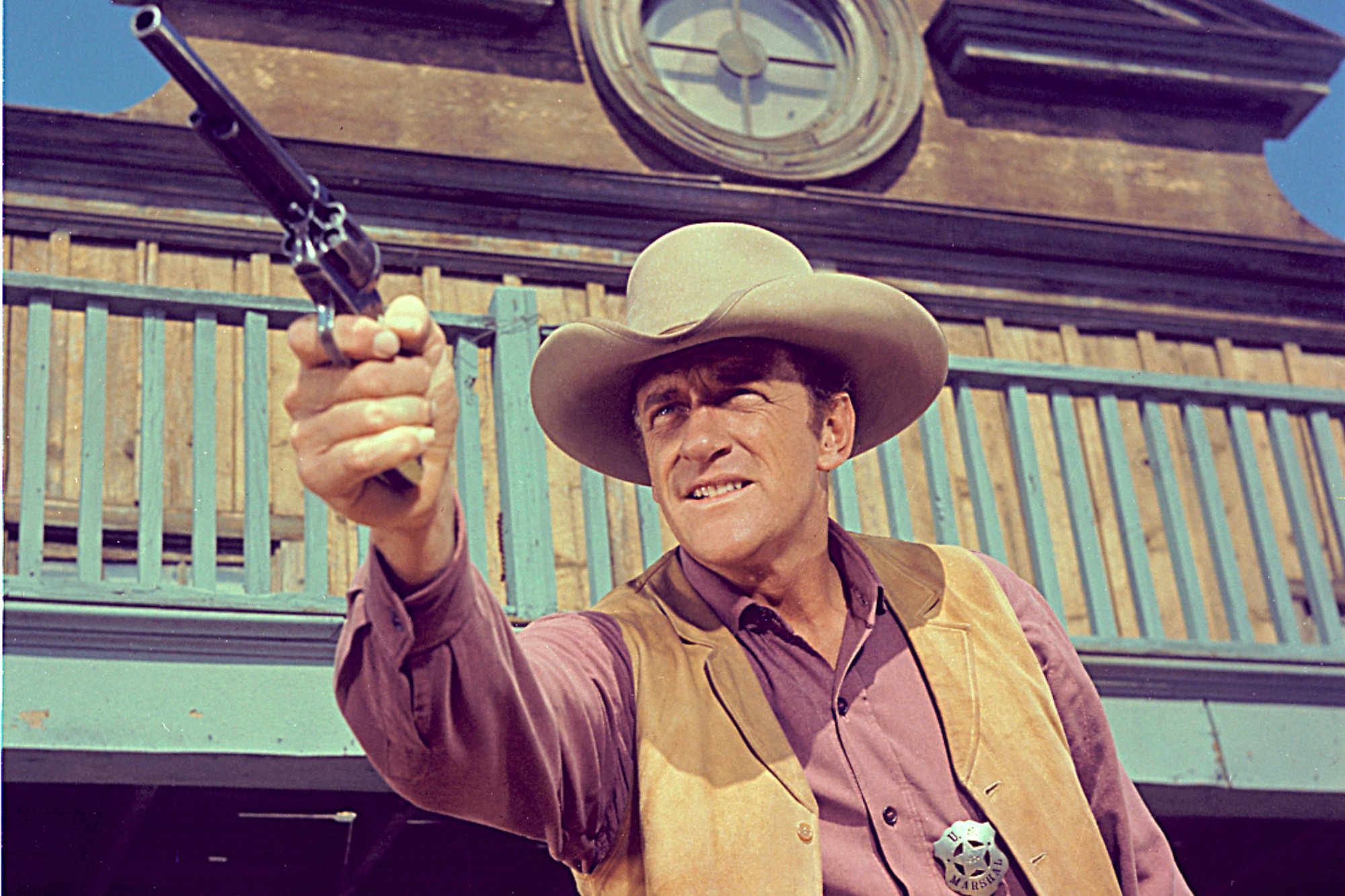 'Gunsmoke' James Arness as Matt Dillon, one of the lead characters pointing his gun out in front of the saloon