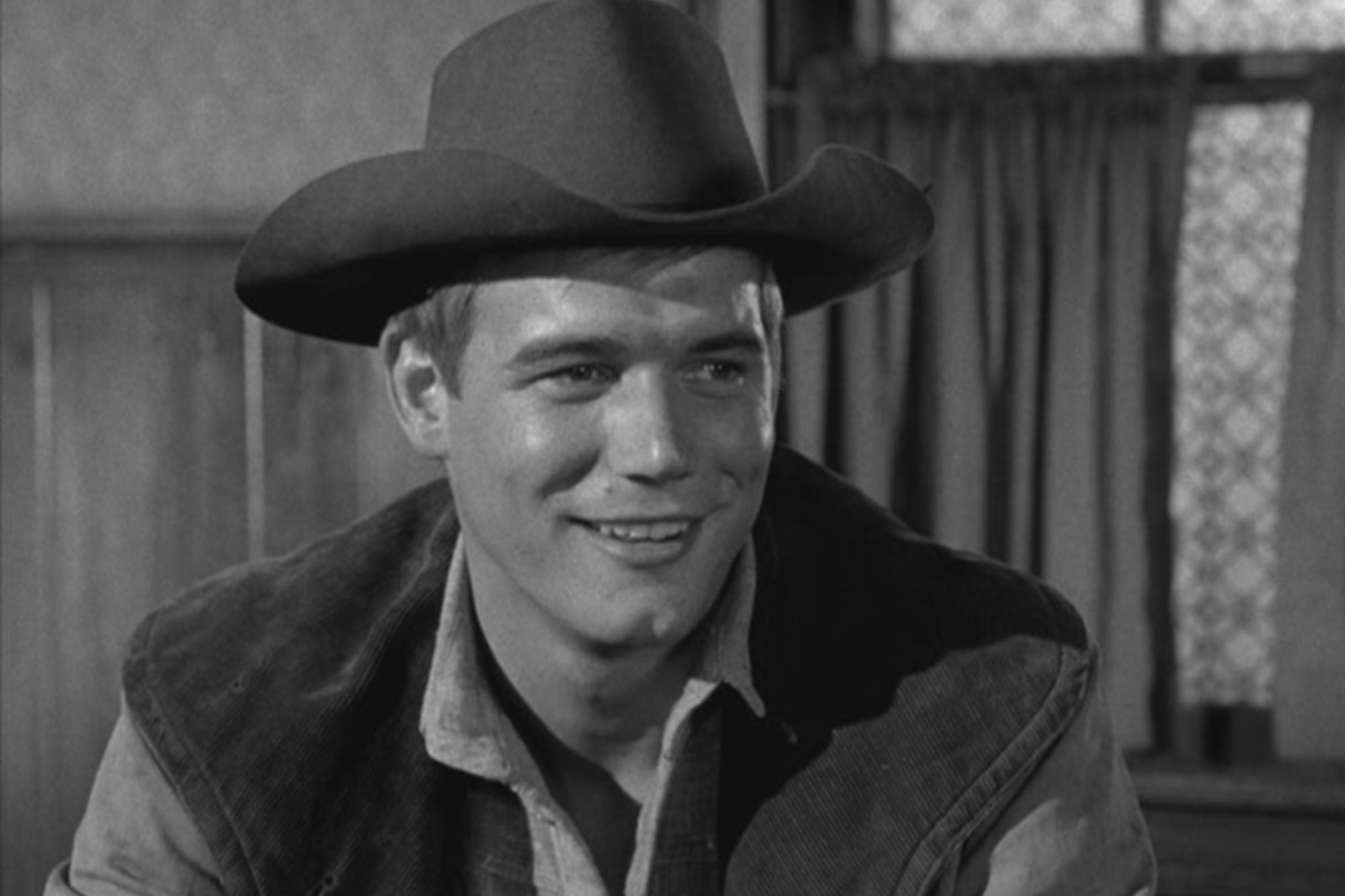 'Gunsmoke' Roger Ewing as Thad Greenwood in a black-and-white picture wearing a cowboy hat, vest, and collared shirt. He's smiling in the picture.
