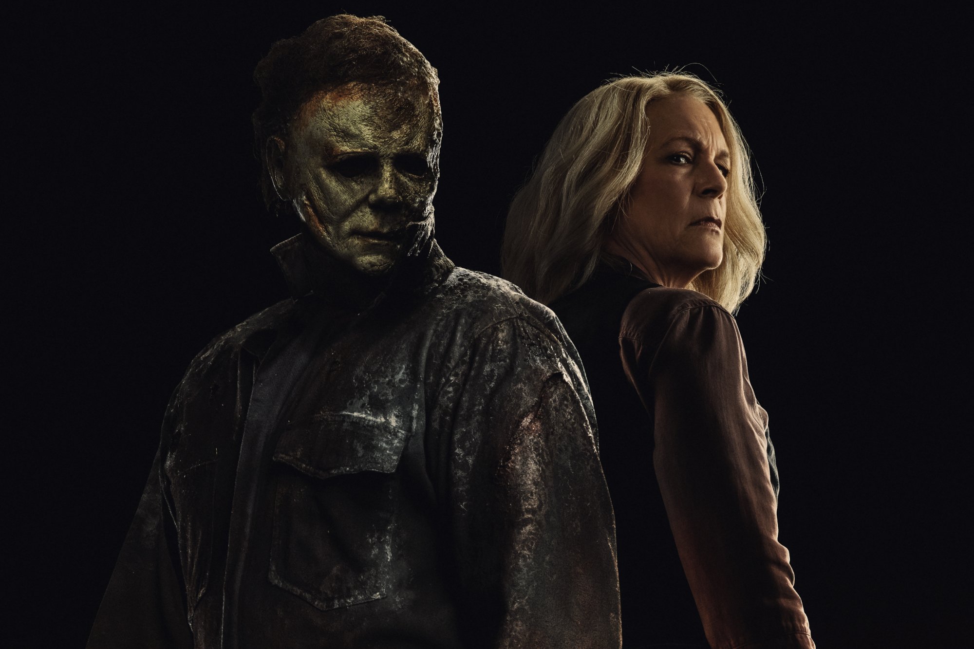 'Halloween Ends' James Jude Courtney as Michael Myers and Jamie Lee Curtis as Laurie Strode in trilogy ending. They're standing back-to-back in front of a black background.