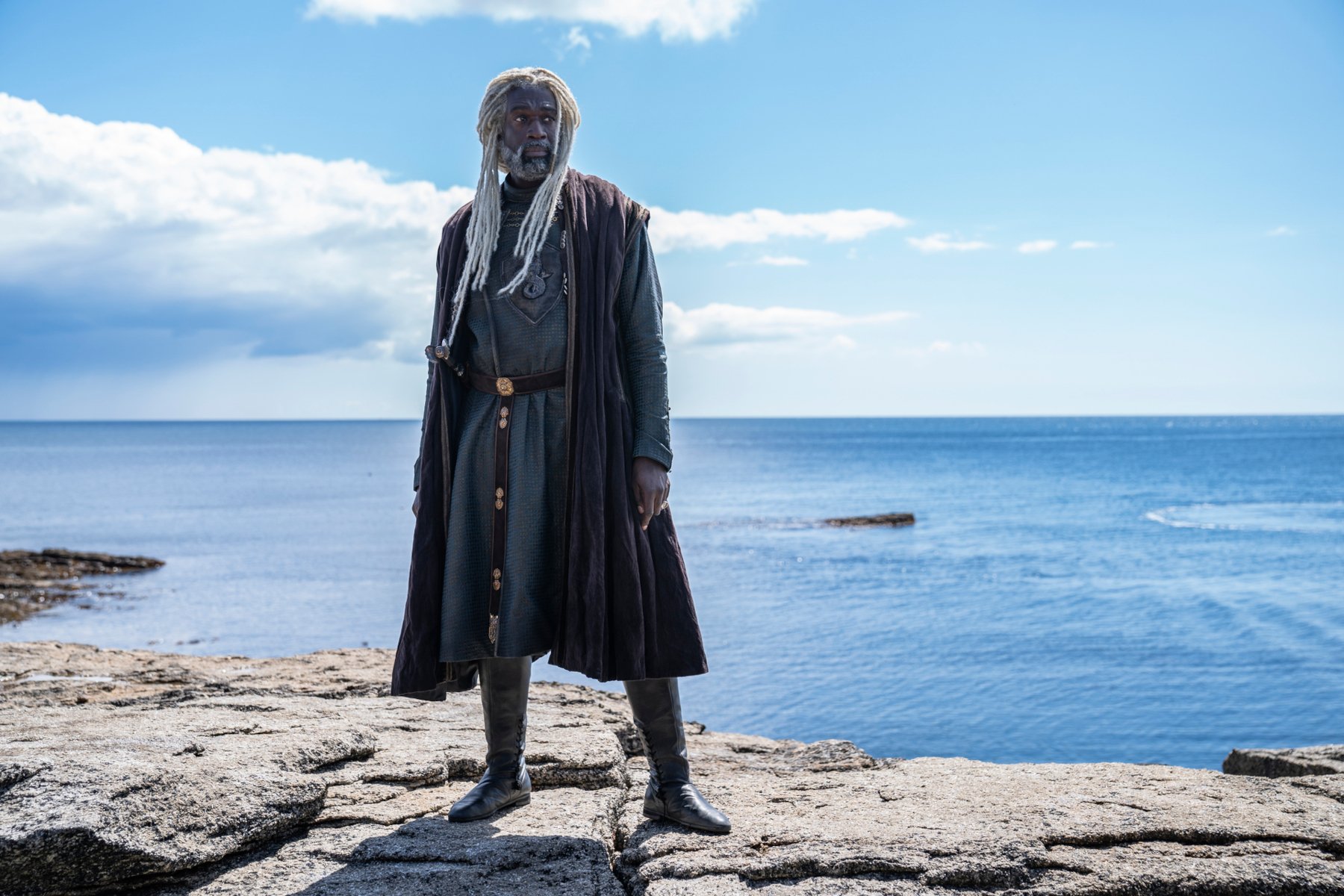 Steve Toussaint as Corlys Velaryon in 'House of the Dragon.' He's wearing a long coat and standing in front of the sea.
