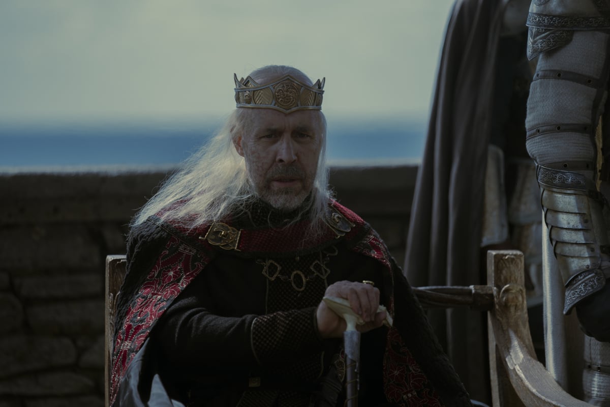 Paddy Considine as King Viserys in House of the Dragon. Viserys is seated, wearing a crown and holding a cane.