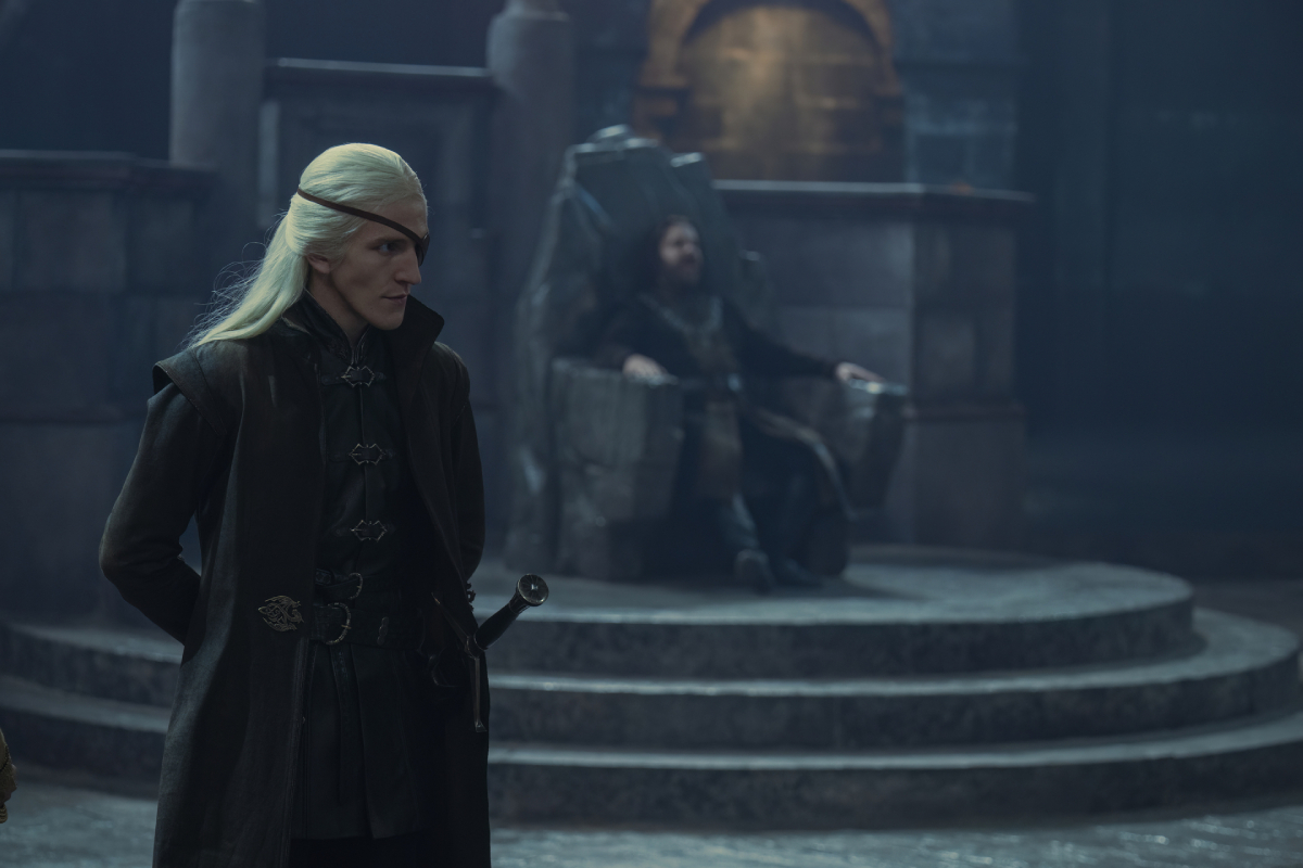 Aemond Targaryen in the House of the Dragon finale. Aemond stands in front of the throne where Lord Baratheon is seated at Storm's End. 