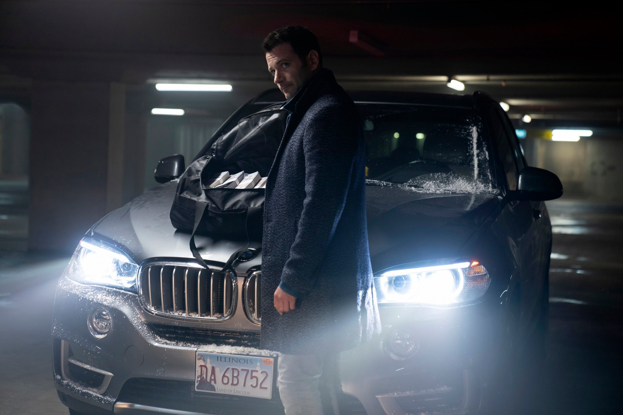 'Irreverent' on Peacock: Colin Donnell as Mack/Paulo standing in front of a car
