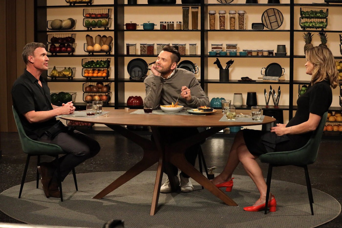 Celebrity Beef host Joel McHale sits at a table and eats pasta in between Jeff Lewis and Miss Pyle