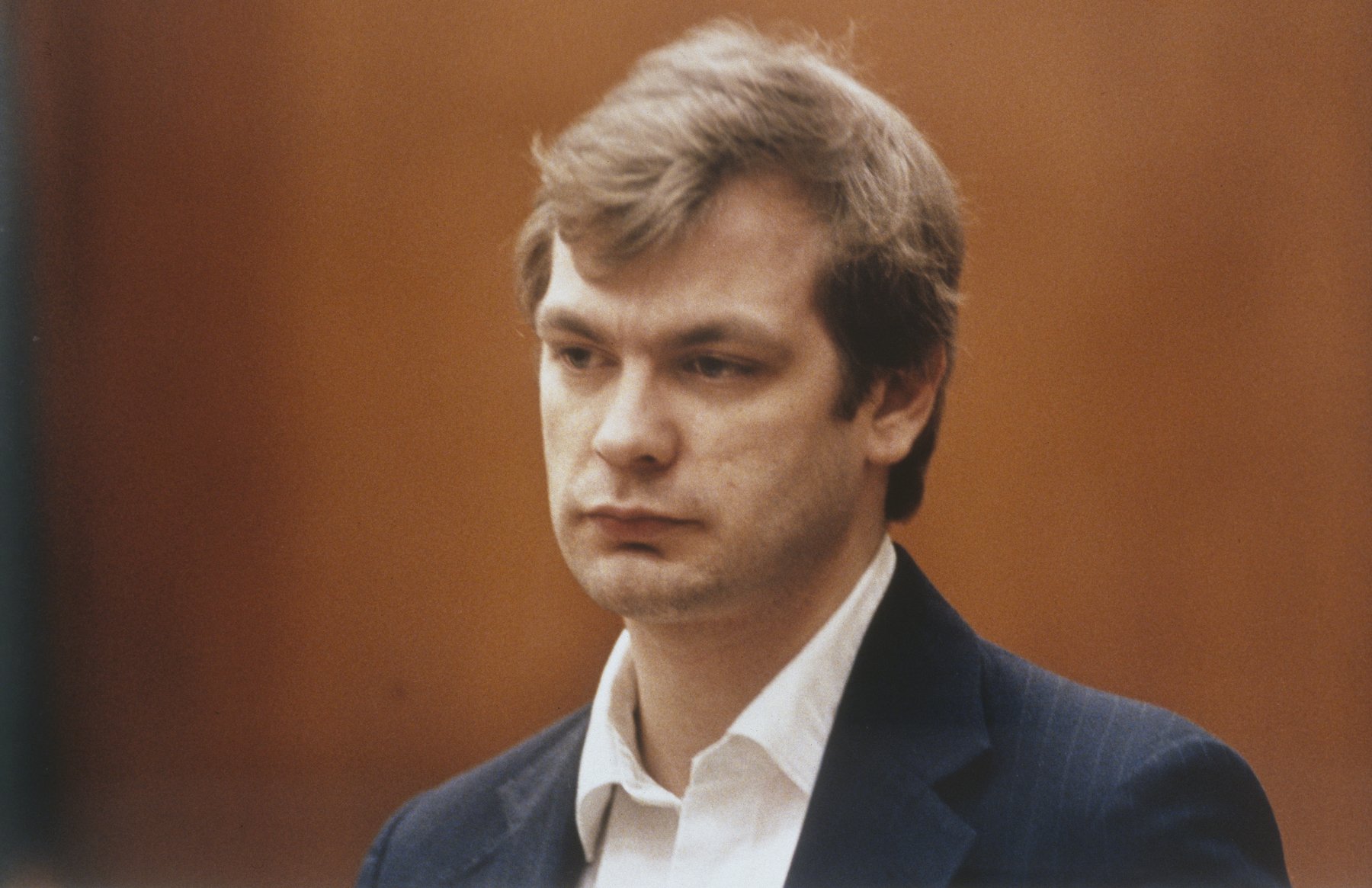 Jeffrey Dahmer, whose glasses are for sale, on a brown background.