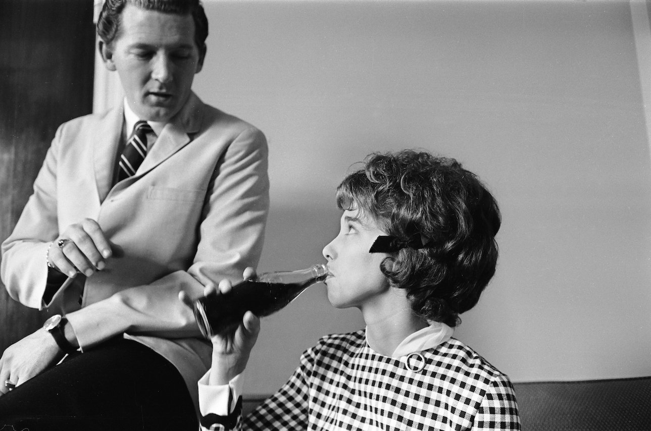 Jerry Lee Lewis talking to his third wife, Myra Gale Brown, while she drinks from a soda bottle