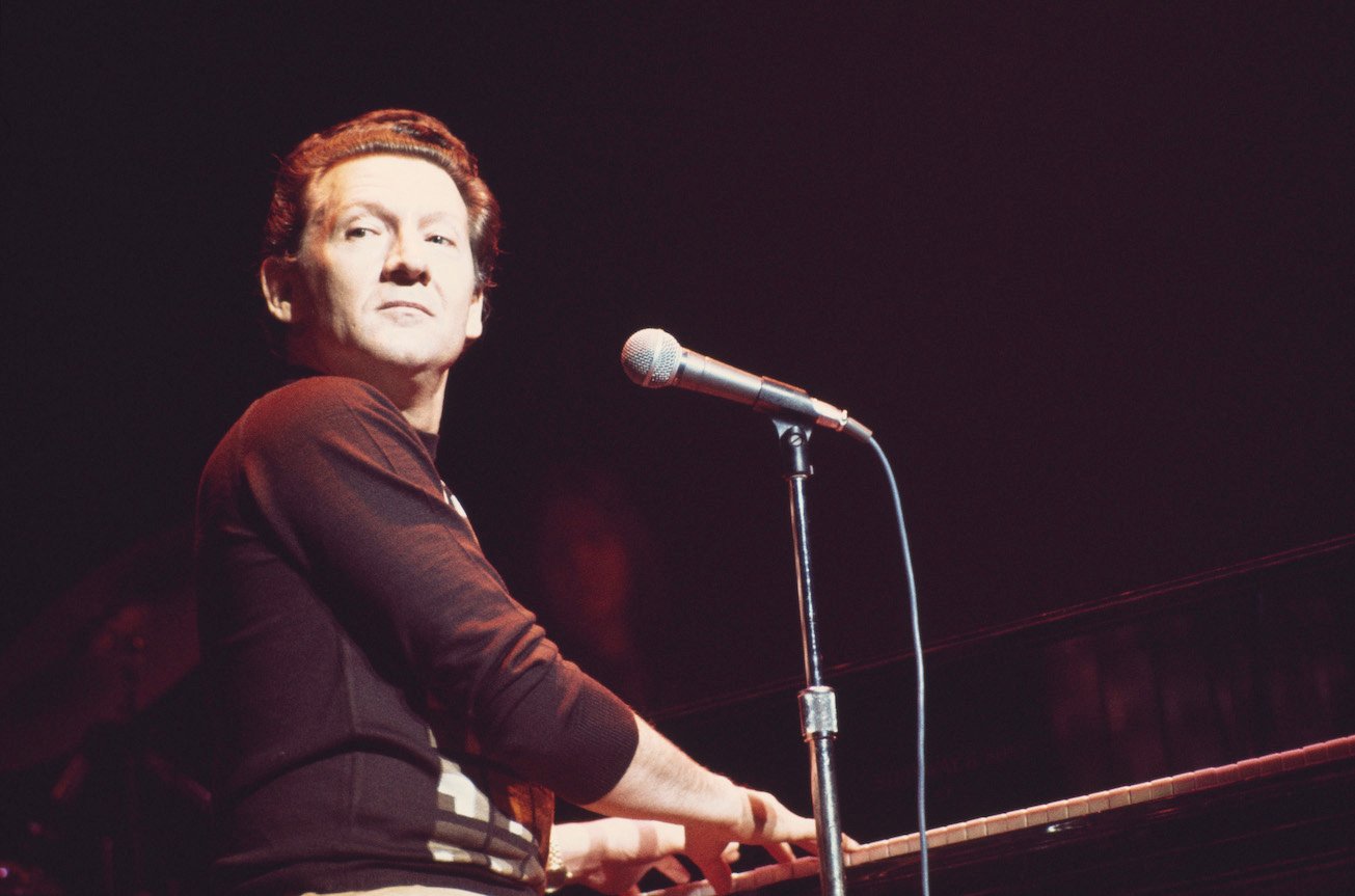 Jerry Lee Lewis at his piano against a dark background