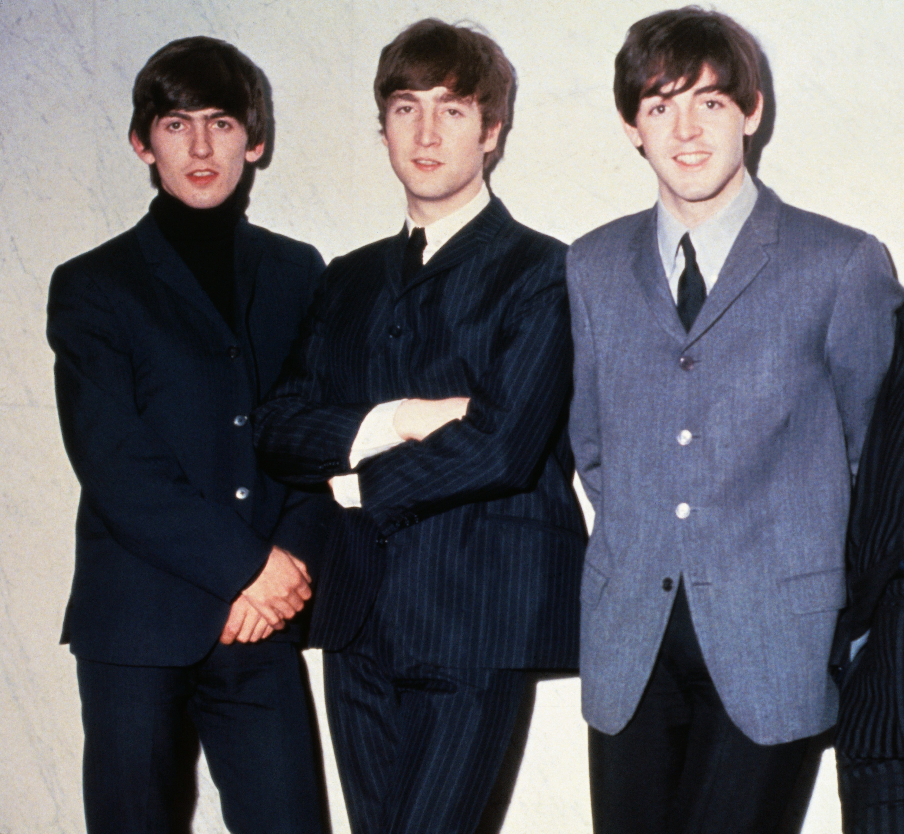 The Beatles' George Harrison, John Lennon, and Paul McCartney near a wall