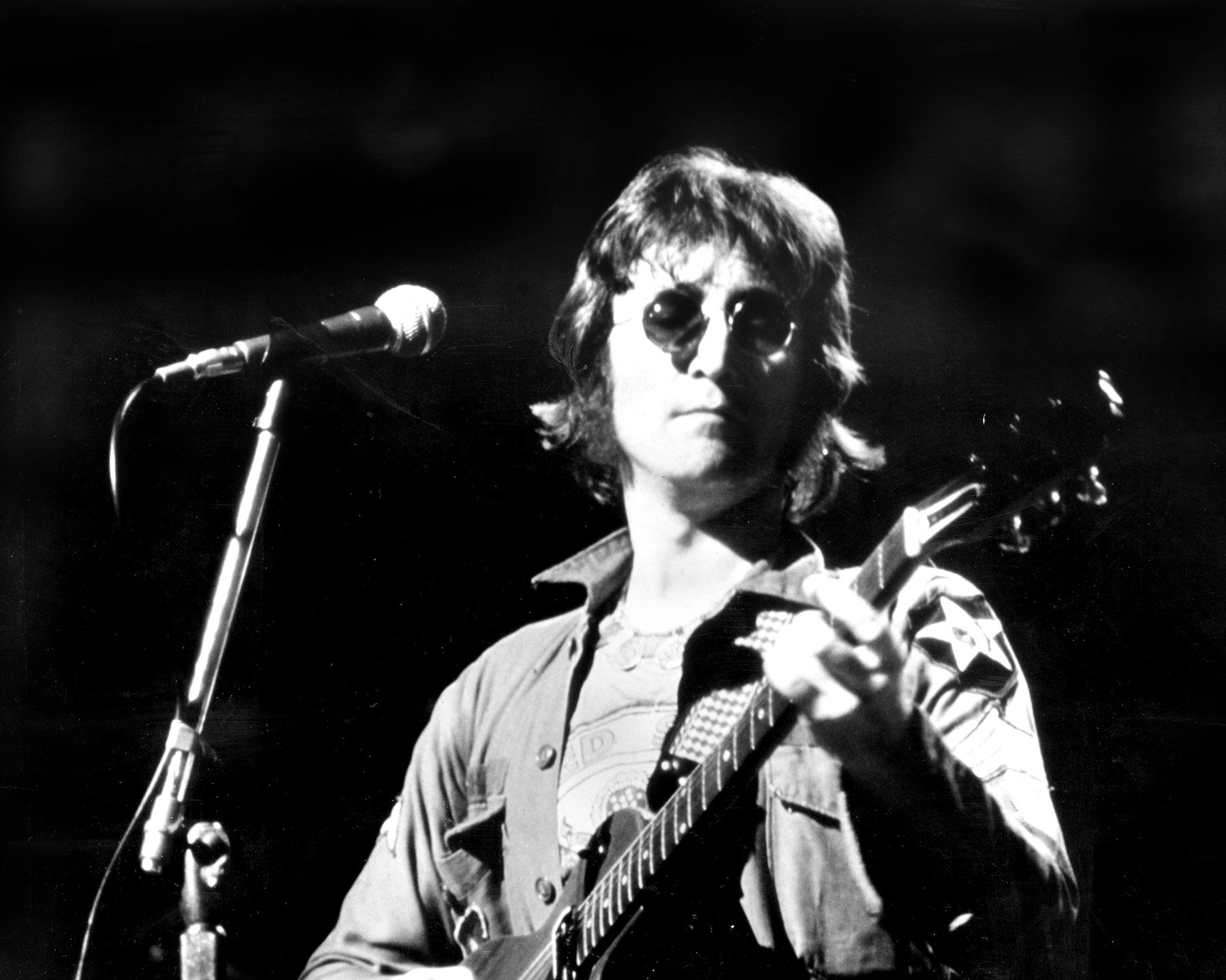 John Lennon, whose parents met in an interesting way, playing guitar