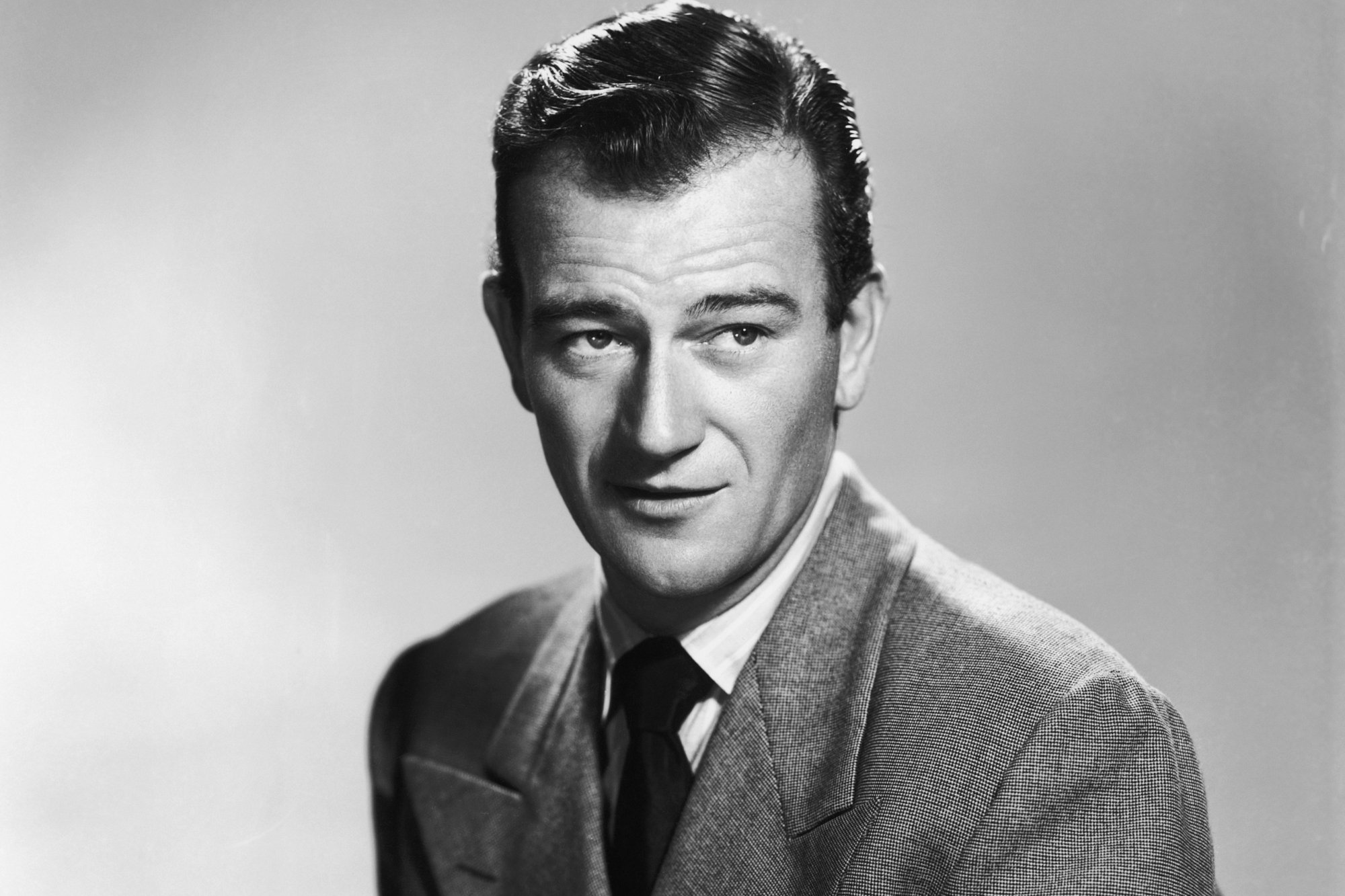 John Wayne, who loved Halloween candy, in a black-and-white photograph wearing a suit