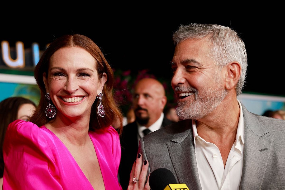 Julia Roberts and George Clooney speak to a journalist at the premiere of "Ticket to Paradise"