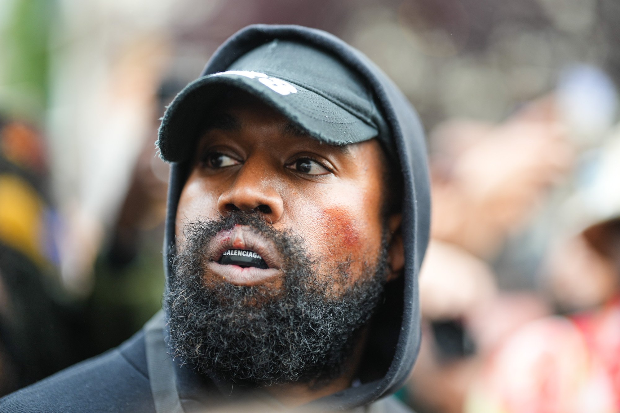 Kanye West, who once had a business relationship with Adidas, wearing a black hat and hoodie