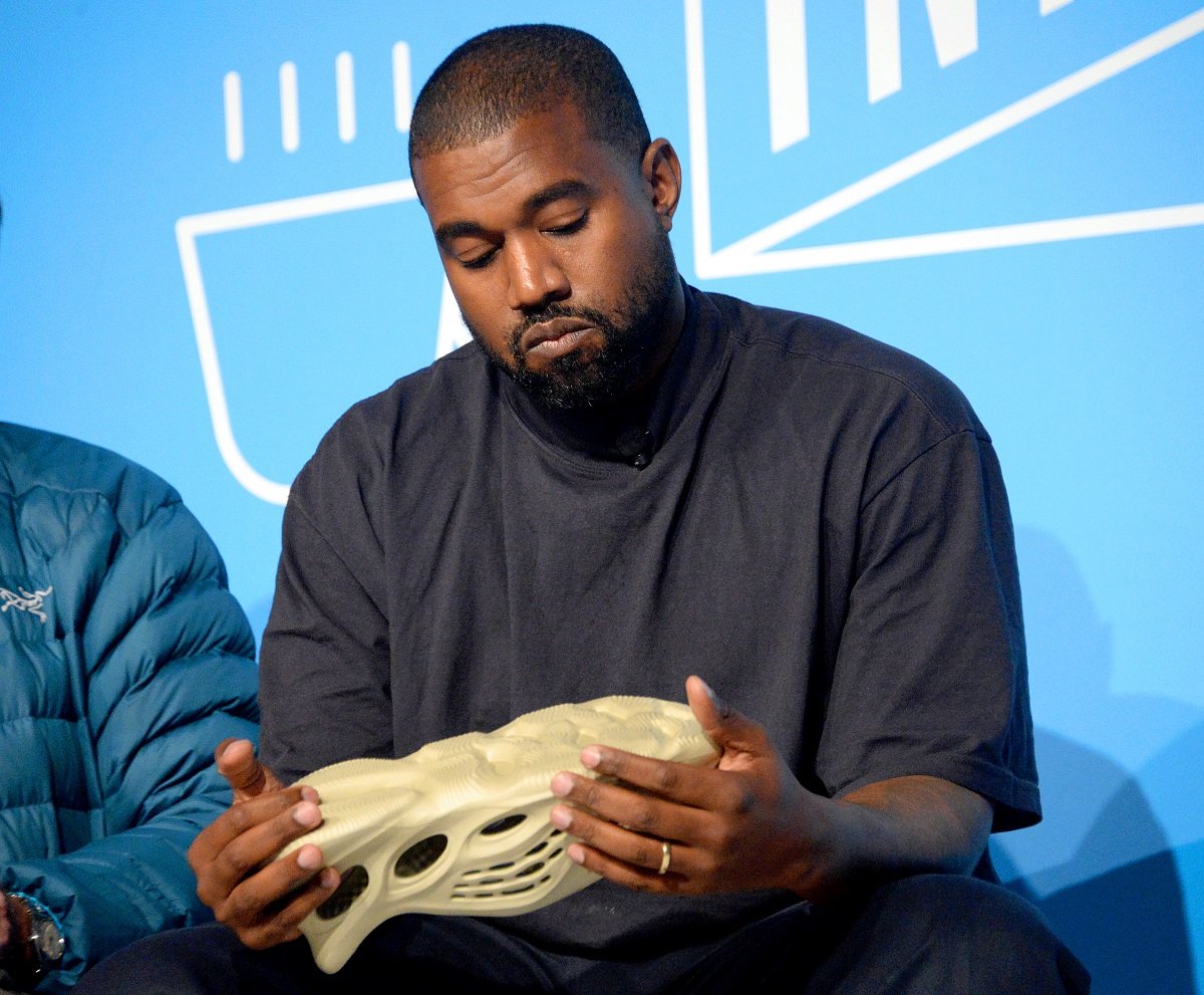 Kanye West holds one of his Yeezy sneakers while he speaks on stage at "Kanye West and Steven Smith in Conversation with Mark Wilson" at the on November 07, 2019 in New York City.