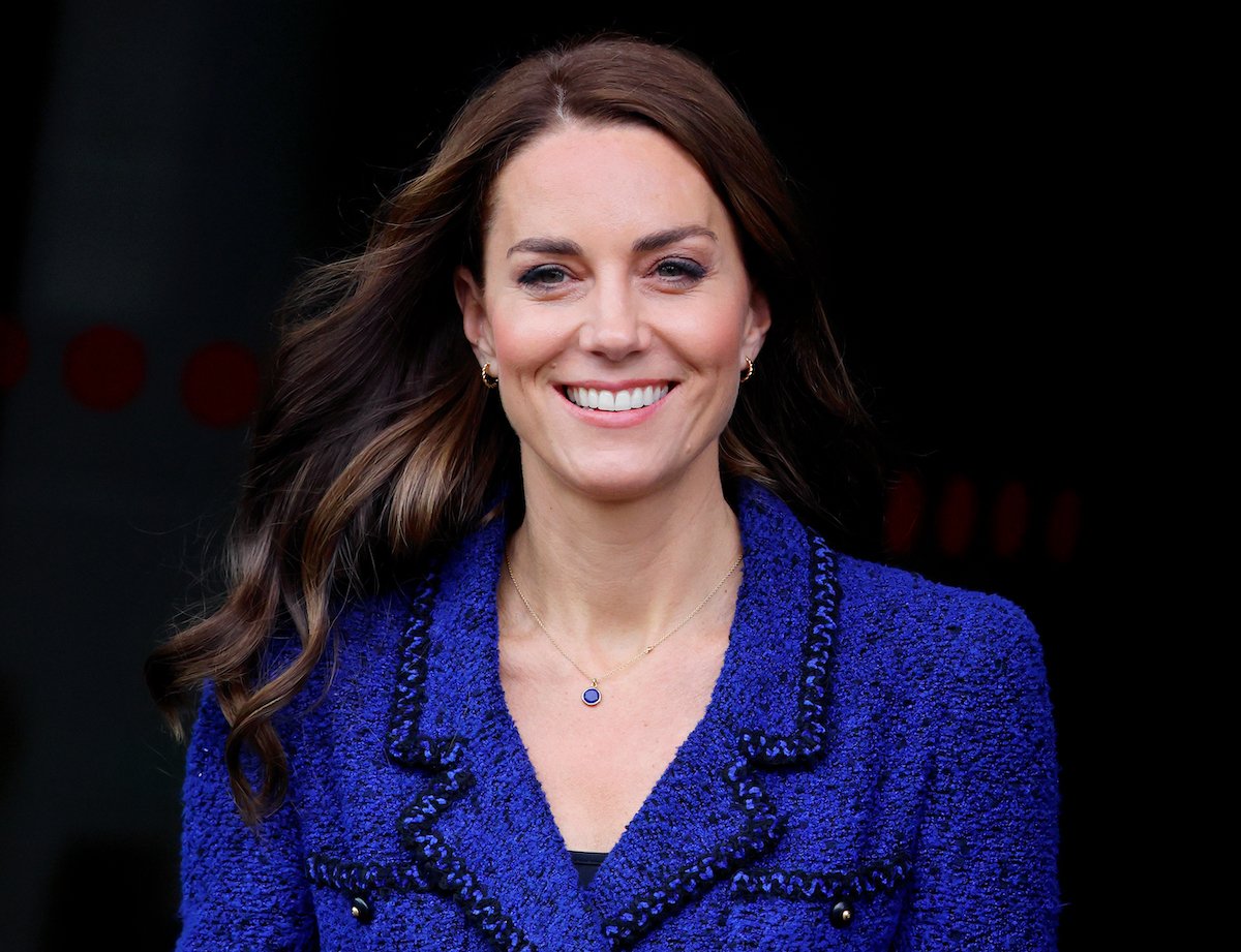 Kate Middleton, whose 'long courtship' with Prince William was vital to her success in the royal family according to Katie Nicholl, smiles wearing a blue blazer