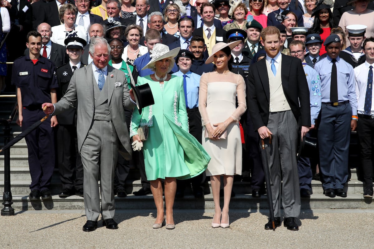 King Charles and Camilla Parker Bowles stand next to Meghan Markle and Prince Harry, who, according to an expert it may not be 'impossible' to regain use of their HRH titles, in 2018