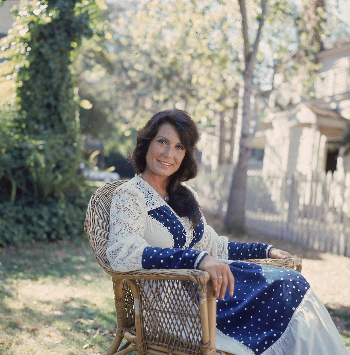 Loretta Lynn sitting outside in a rocking chair in the 1970s