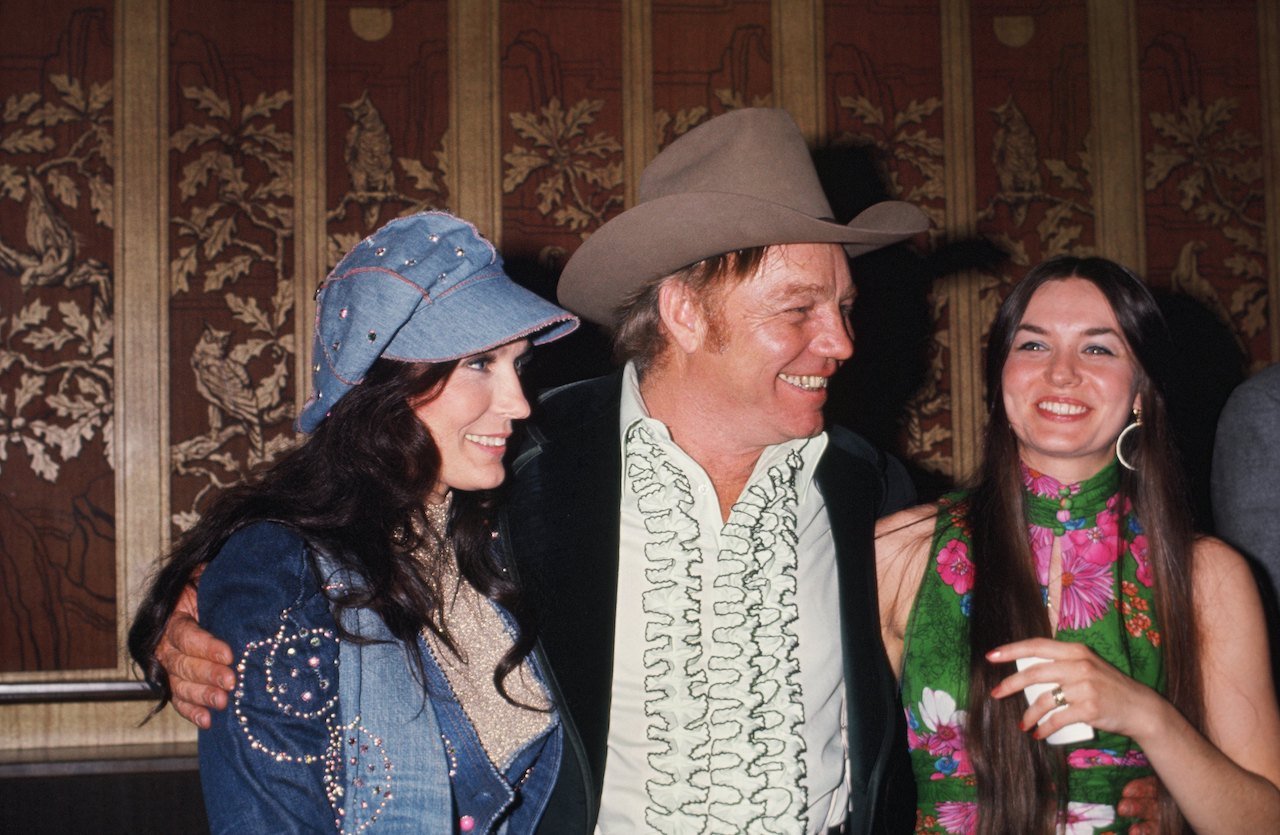 Sisters Loretta Lynn (left) and Crystal Gayle (right) flank Loretta's husband Oliver Lynn at a soiree, circa 1976. Lynn once said Oliver 'ran around' on her from the start of their marriage.