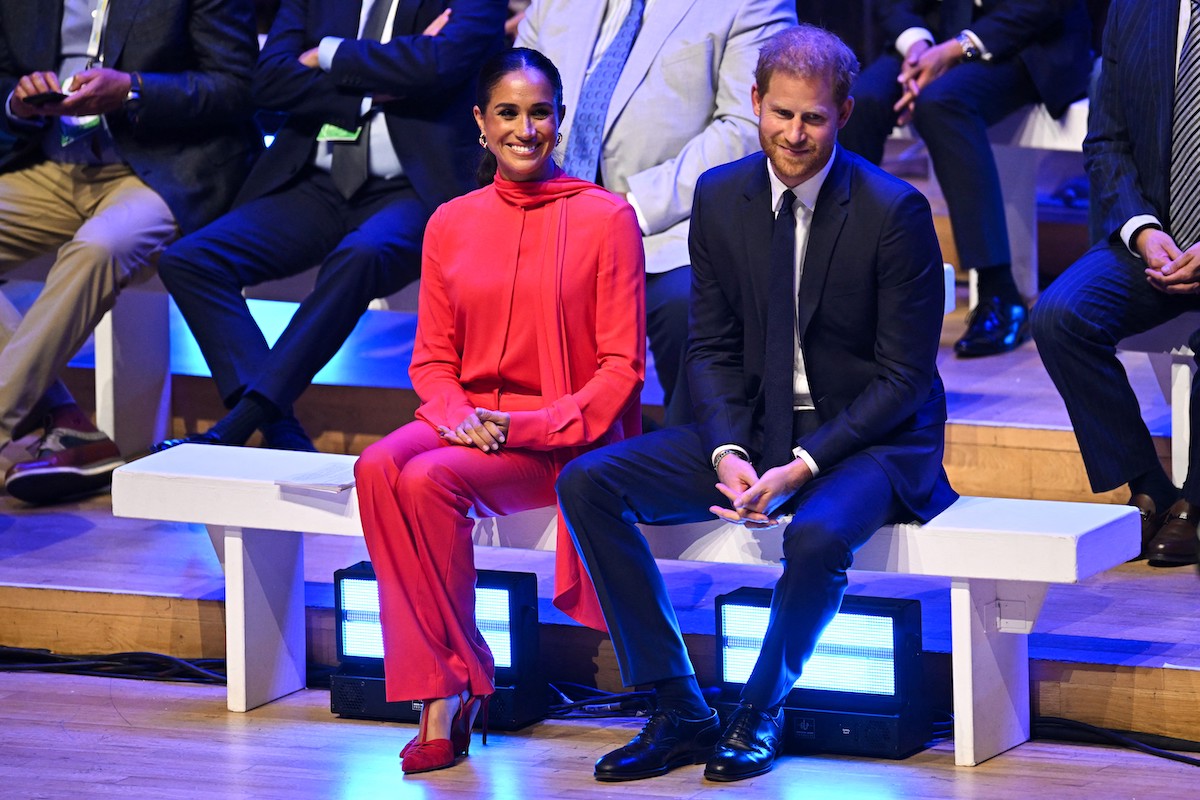 Meghan Markle, who was told to dress more like Kate Middleton according to Katie Nicholl's 'The New Royals' book, wears designer clothing as she sits next to Prince Harry at the One Young World Summit opening ceremony