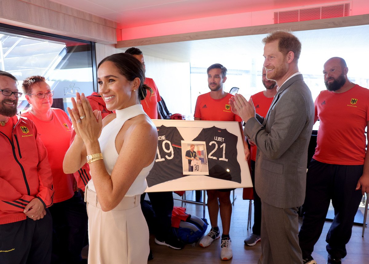 Meghan Markle and Prince Harry, whose son Archie Harrison Mountbatten-Windsor celebrates his fourth birthday on May 6, 2023, the same day as King Charles's coronation, clap as they receive custom jerseys for Archie and Lilibet Diana Mountbatten-Windsor