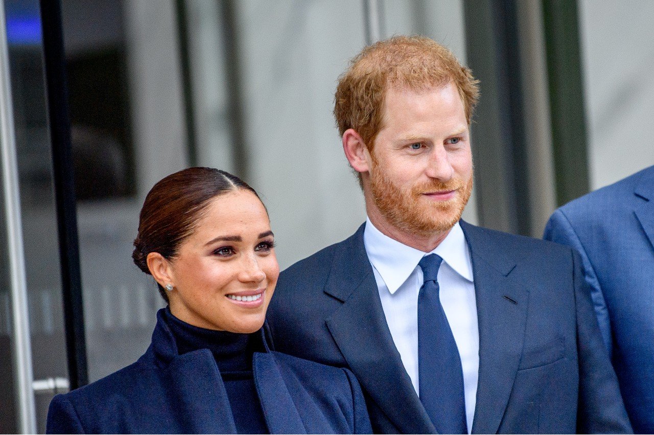 Meghan Markle stand next to each other while wearing blue outfits.